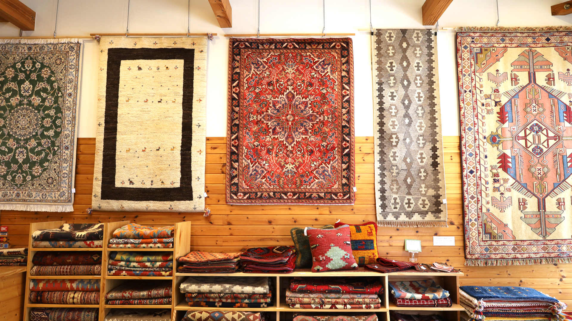 ギャッベを含む、多彩なペルシャ絨毯が並ぶクラフトワーク店内。毛足のない織物、キリムも扱っています。